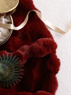 a close up of a red fur with a white ribbon on the end and a round object next to it