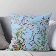 a blue pillow sitting on top of a couch next to a white pillow with red flowers