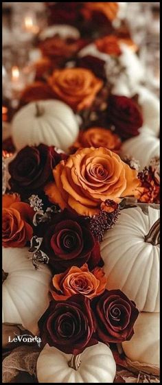 there are many flowers and pumpkins on this long table cloth with candles in the background