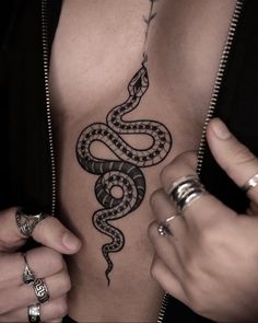 a man with a snake tattoo on his chest and hand in the other hand,