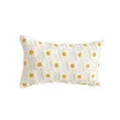 a white and yellow pillow with flowers on the front, sitting against a white background