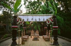 an outdoor ceremony setup with chairs and candles on the stage, surrounded by greenery