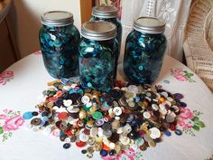 three jars filled with buttons sitting on top of a table