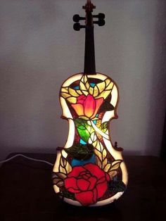 a stained glass violin with roses on it's back and the neck is sitting on a table