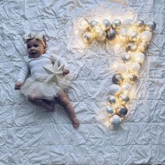 a baby is laying on a bed with christmas ornaments around it and the letter p spelled out