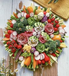 an arrangement of vegetables arranged in a circular arrangement on a wooden surface with flowers and herbs