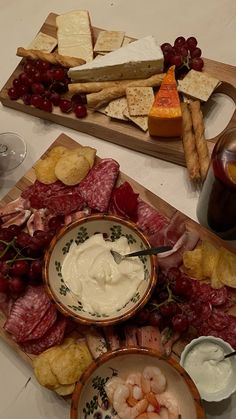 two trays filled with different types of food on top of a table next to wine glasses