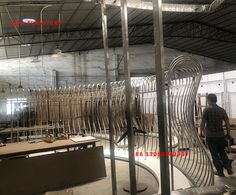 a man standing in front of a large metal sculpture inside of a room filled with tables and chairs