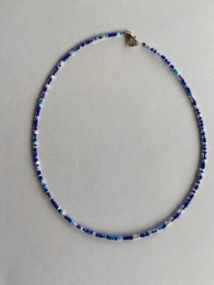 a blue and white beaded necklace on a white surface