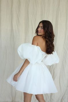 a woman in a white dress posing for the camera with her hands on her hips