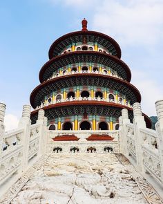 a tall building with many windows and arches on top of it's sides in front of a cloudy blue sky