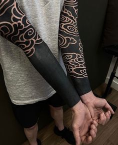 two people holding hands with tattoos on their arms