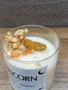 a glass filled with milk and flowers on top of a wooden table