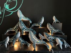 a group of blue and white ceramic dolphins on display in a room with black walls