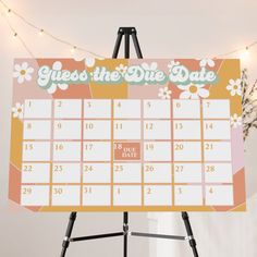 a calendar on a tripod stands in front of a white wall with string lights