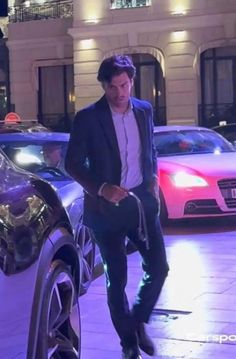 a man in a suit is standing next to a car