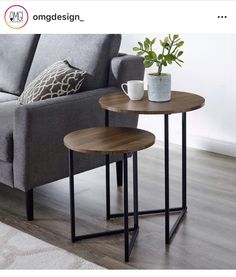 two tables sitting on top of a wooden floor next to a gray couch and white rug