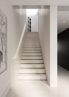 there is a staircase leading up to the second floor in this modern house with black and white artwork