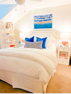 a bedroom with white bedding and blue pillows