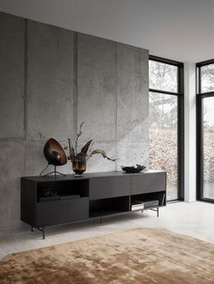 a living room with large windows and a brown rug on the floor in front of it