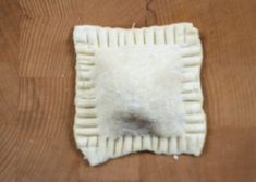 a piece of food sitting on top of a wooden table next to a white object