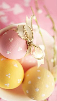 some eggs are sitting in a bowl on a pink tablecloth with white polka dots