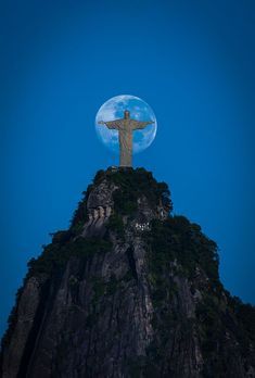 the christ statue is on top of a mountain with a full moon in the background