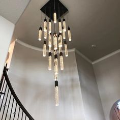 a chandelier made out of glass bottles hanging from the side of a spiral staircase