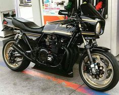 a black and gold motorcycle parked in front of a gas station booth with the door open