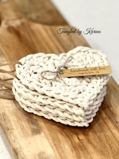 two white crocheted heart shaped coasters on a wooden board with a tag