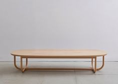 an oval wooden table sitting in front of a white wall