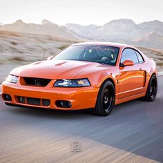 an orange sports car driving down the road