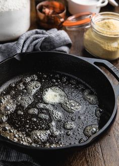 a frying pan filled with oil on top of a wooden table next to other ingredients