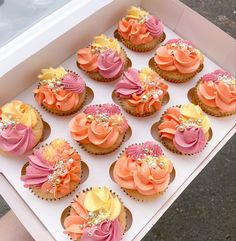 a box filled with cupcakes covered in pink and yellow frosting