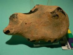 an old piece of pottery is displayed on a blue surface with a rainbow tag in the foreground