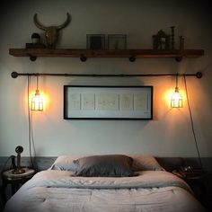 a bed sitting under two lights in a bedroom next to a wall mounted deer head