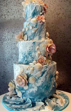 a blue and white wedding cake with seashells on it