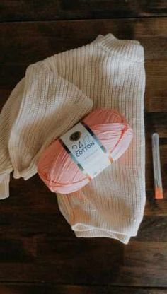 an orange ball of yarn sitting on top of a wooden floor next to a pair of scissors