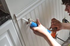 a man is working on a wall with a paint roller in his hand and an open can