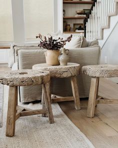 two wooden stools sitting next to each other on top of a rug in front of a couch