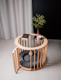 a dog bed in the shape of a cage with a plant on top and a book next to it