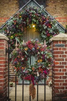 a christmas wreath is hanging on the front gate of a brick building with an iron fence