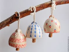 three ceramic bell ornaments hanging from a tree branch