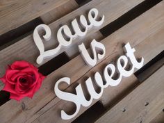 two wooden letters that say love is sweet and one with a red rose on it