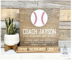 a wooden sign that says coach jayson and has a baseball on it next to a potted plant