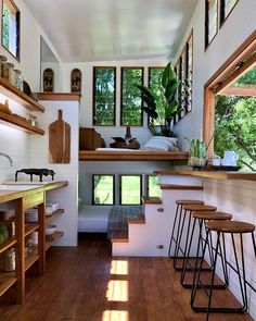 the interior of a tiny house with wood floors and shelves on each side, along with wooden stools