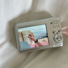 a person is holding an open book in their hand while laying on a white sheet