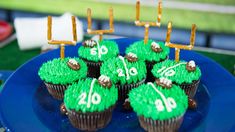 cupcakes decorated with green frosting and gold numbers are on a blue plate