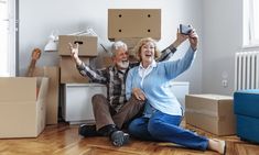 an older man and woman sitting on the floor with moving boxes in front of them