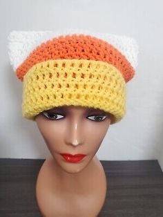 a mannequin head wearing a crocheted hat with orange, white and yellow colors